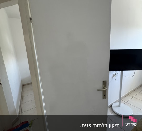 דלת לבנה פתוחה עם ידית מתכת בחדר